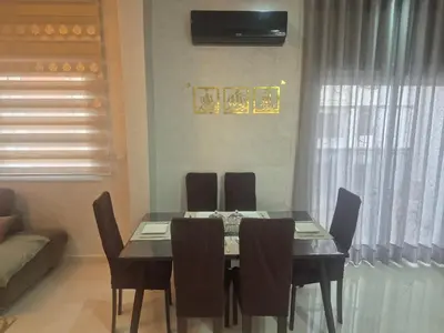 a dining room with a table and chairs and a couch at Maison intelligente, idéale pour les familles avec Netflix, parking et ascenseur in Fès