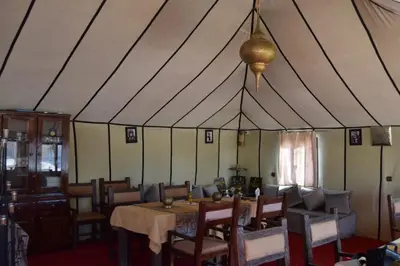 a dining room with a table and chairs in a tent at Sahara Spirit Luxury Camp in Merdani