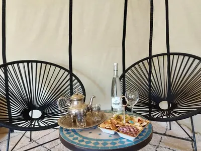 a table with a plate of food and a bottle of wine at Sahara Spirit Luxury Camp in Merdani