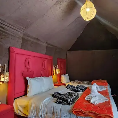 a bedroom with a bed with a pink head board at Sahara Spirit Luxury Camp in Merdani