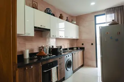 a kitchen with white cabinets and a washer and dryer at Appartement de luxe avec piscine - Agadir Bay in Oulad Akkou