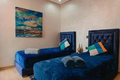 a bedroom with two beds and a painting on the wall at Appartement de luxe avec piscine - Agadir Bay in Oulad Akkou