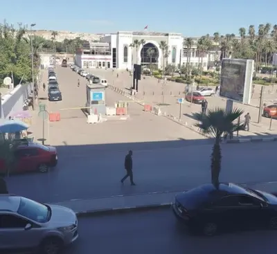a man walking down a street with cars in a parking lot at PAUSE HOUSE-Downtown-Front of Station-Airport Bus-FREE COUSCOUS Friday in Fès
