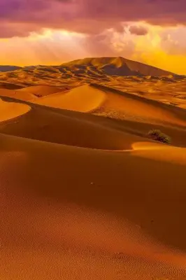 a view of a desert with a sunset in the background at Itran desert camp in Merzouga