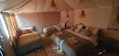 a room with three beds in a tent at Itran desert camp in Merzouga