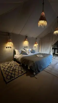 a bedroom with a bed in a room with lights at Itran desert camp in Merzouga