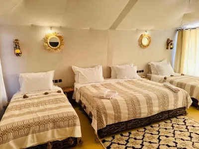 a bedroom with two beds and a mirror on the wall at Brilliant luxury camp in Merzouga