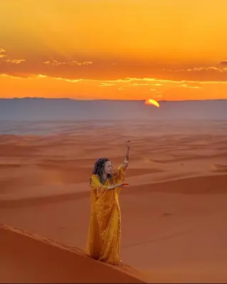 a woman standing in the desert throwing a frisbee at Brilliant luxury camp in Merzouga