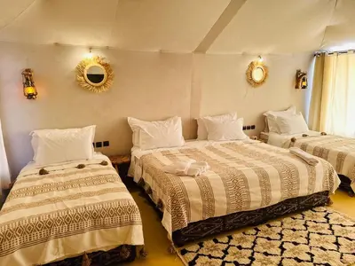 a bedroom with two beds and a mirror on the wall at Brilliant luxury camp in Merzouga