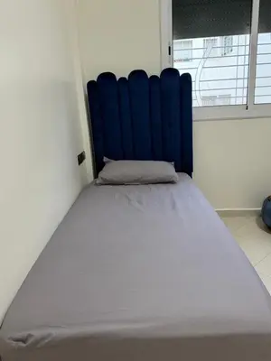a bed with a blue headboard in a room at Apartment in downtown Fez in Fès