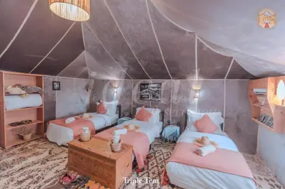 a room with three beds and a table in a tent at Bivouac luxury camp in Merzouga
