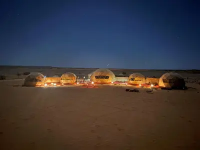 a group of tents in the desert at night at Bivouac luxury camp in Merzouga