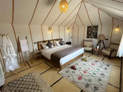 a bedroom with a bed and a chair in a room at Bivouac luxury camp in Merzouga
