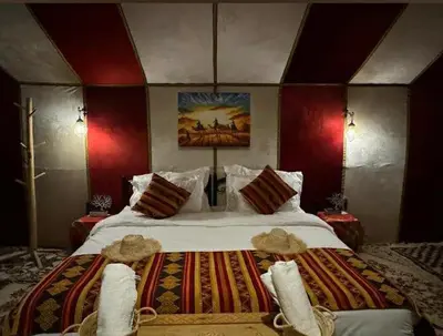 a bedroom with a large bed with red walls at Bivouac luxury camp in Merzouga