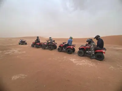 a group of people riding atvs in the desert at Desert Family Camp in El Gouera