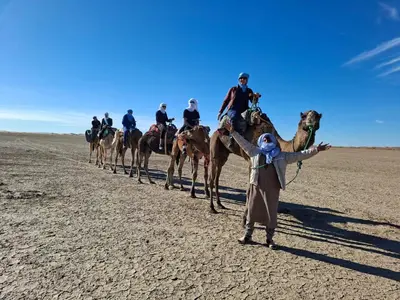 a group of people riding on camels in the desert at Milky Way Chigaga Camp in El Gouera
