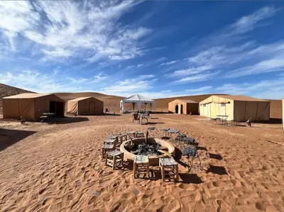 a group of tents and tables in the desert at Milky Way Chigaga Camp in El Gouera