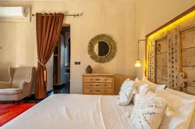 a bedroom with a bed and a chair and a mirror at Villa Chocolat in Marrakech