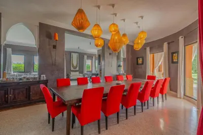 a dining room with a long table and red chairs at Villa Chocolat in Marrakech