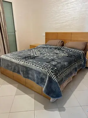 a bed with a black and white blanket on it at Appartement Diyar Saiss in Meknès