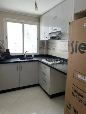 a kitchen with white cabinets and a black counter top at Appartement Diyar Saiss in Meknès