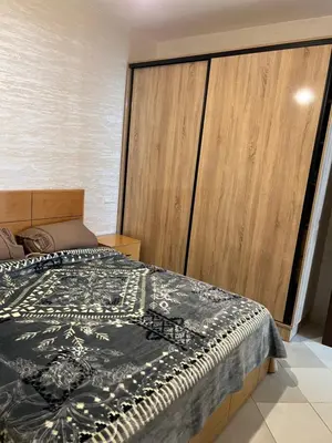 a bedroom with a bed and a large wooden cabinet at Appartement Diyar Saiss in Meknès