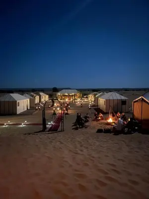 a group of people sitting on a beach at night at Azalai Haven Camp in Merzouga