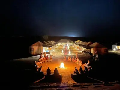 a group of people sitting around a fire at night at Azalai Haven Camp in Merzouga