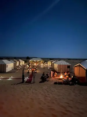 a group of tents in the desert at night at Azalai Haven Camp in Merzouga