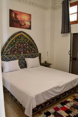 a bedroom with a large bed with a large headboard at dar andalosse fes in Fès