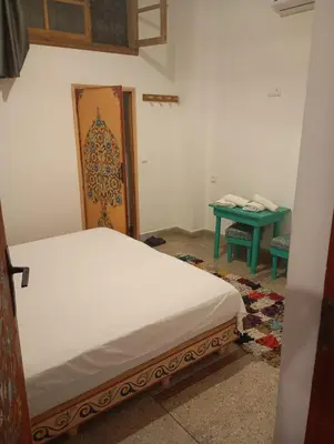 a bedroom with a bed and a green table at dar andalosse fes in Fès