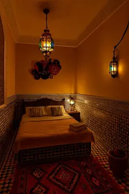 a bedroom with a bed and a chandelier at Riad jnan lward in Fès