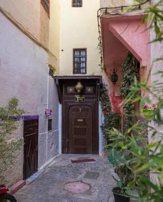 an alley with a large wooden door in a building at Riad jnan lward in Fès