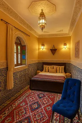 a bedroom with a bed and two blue chairs at Riad jnan lward in Fès