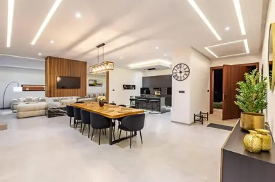 a dining room and living room with a table and chairs at Hidaya Villa - Heated Pool, Padel , Spa & Gym in Najem
