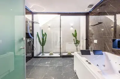 a bathroom with a tub and a glass shower at Hidaya Villa - Heated Pool, Padel , Spa & Gym in Najem