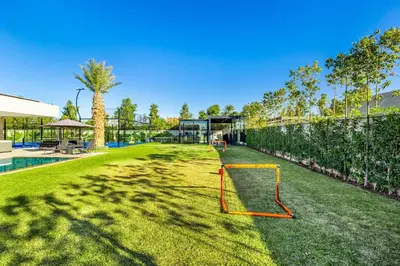 a yard with a net on the grass at Hidaya Villa - Heated Pool, Padel , Spa & Gym in Najem