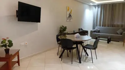 a living room with a table and chairs and a tv at Annakhil 30 in Oulad Akkou