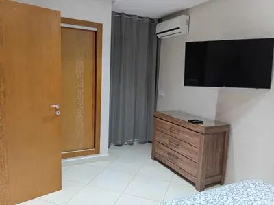 a room with a television on a wall with a dresser at Annakhil 30 in Oulad Akkou