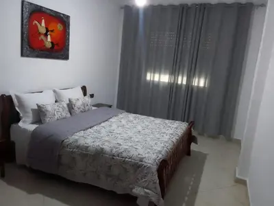 a bedroom with a bed and a window with curtains at Touahri C TW01 Apartment - Centre in Oulad Akkou