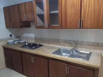 a kitchen with a sink and wooden cabinets at Touahri C TW01 Apartment - Centre in Oulad Akkou