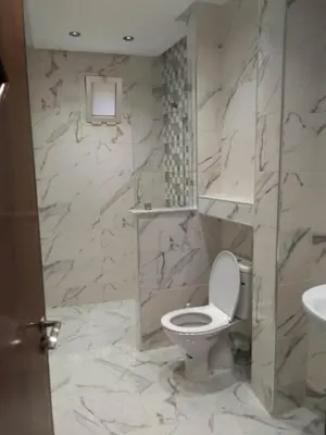 a marble bathroom with a toilet and a sink at Touahri C TW01 Apartment - Centre in Oulad Akkou