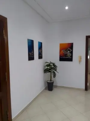 a white wall with three pictures and a potted plant at Touahri C TW01 Apartment - Centre in Oulad Akkou
