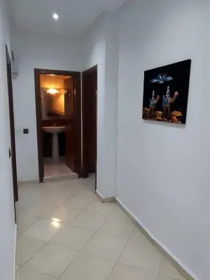 a hallway with a white room with a picture on the wall at Touahri C TW01 Apartment - Centre in Oulad Akkou