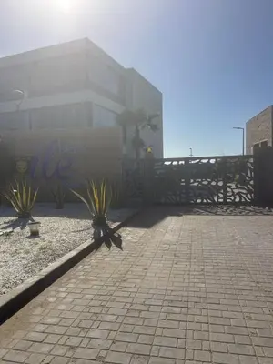 a person standing behind a fence in front of a building at Beach-front paradise with parking and pool in Oulad Akkou