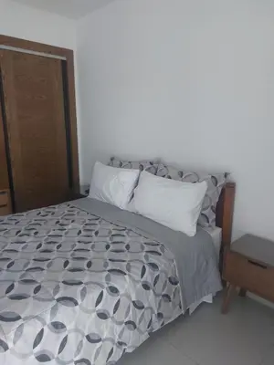 a bed with a gray and white comforter and pillows at Al Anouar B40 in Oulad Akkou