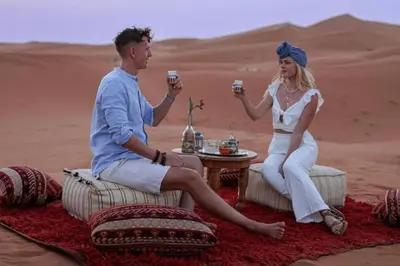 a man and woman drinking coffee in the desert at merzouga asamer in Merzouga