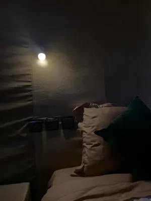 a dark room with a bed and a light on the wall at Azadic luxury tents in Merzouga