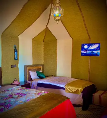 a bedroom with two beds and a chandelier at Azadic luxury tents in Merzouga