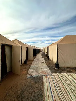 a row of tents are lined up in the desert at Sahara Joy Camp in Merzouga